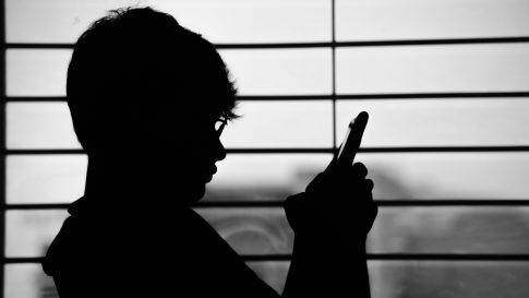 man's shadow watching his cellphone