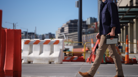 Un homme marche dans la rue avec un ordinateur surface dans la main