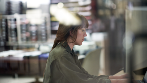 Decision maker creating a survey or taking a security assessment on the warehouse floor of a textile manufacturing plant. Keywords: One person; mobile device; on the go; woman; female manager; operations; CEO; chief executive officer; c-suite; IoT Security; OT Security; factory; monitor and manage security